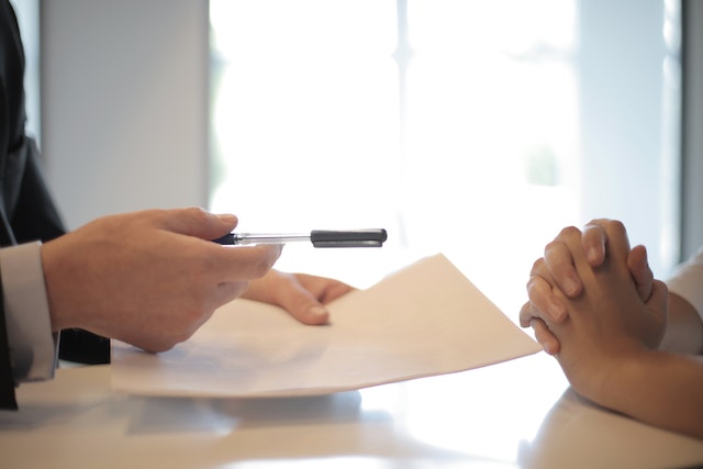 A person handing over a pen and paper