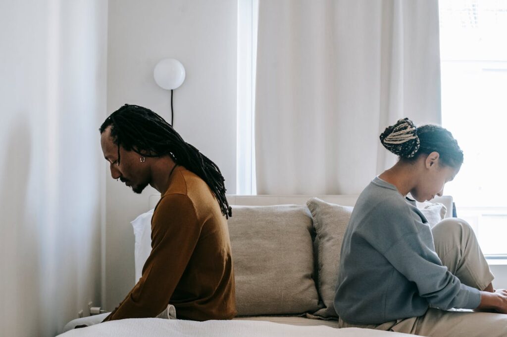 Two people in bed looking sad