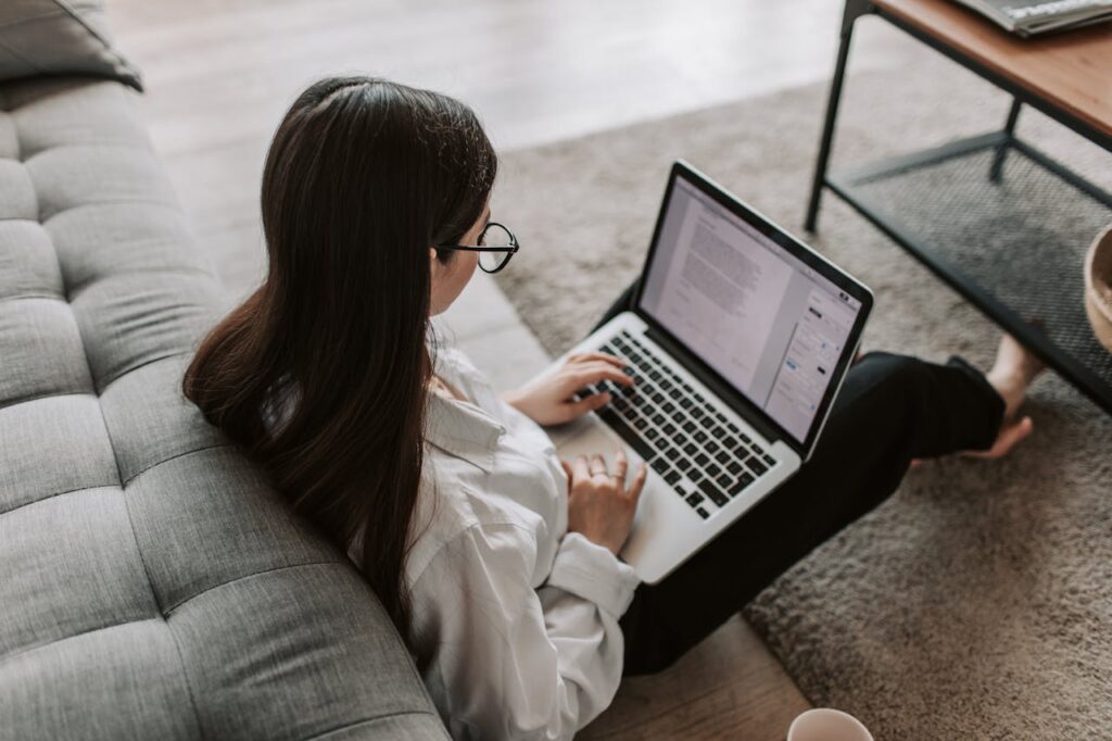 A woman sat on the floor using her laptop